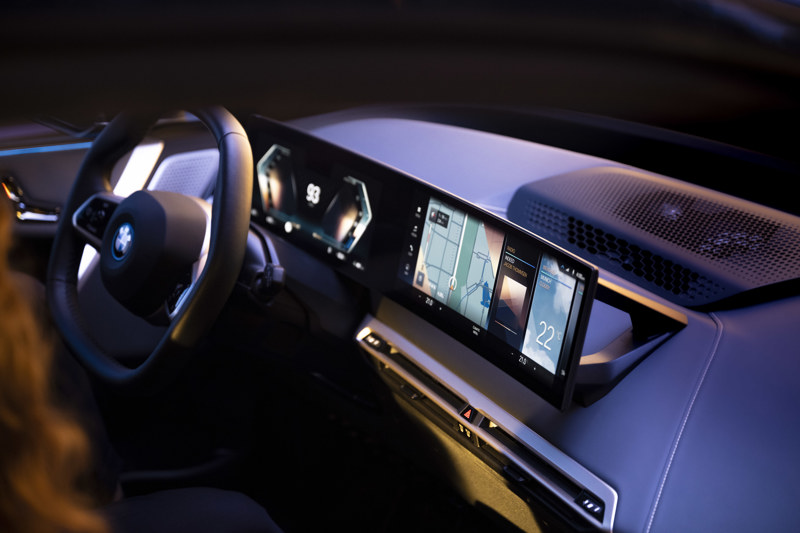 BMW iX med digitalt instrumentpanel och infotainmentskärm monterad på ett fäste på instrumentbrädan.
