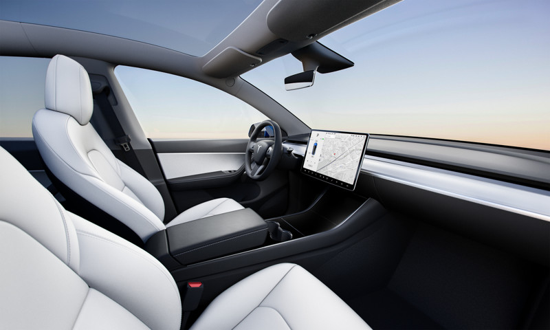 The Tesla Model Y budget design has a single infotainment screen mounted on a bracket in the dashboard's center.